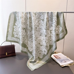Close-up of sage green silk-feel scarf with white floral print and geometric border