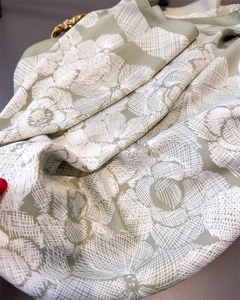 Detailed macro of a light green silk-like scarf with hand-drawn white floral print