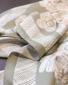 Macro detail of sage green floral silk scarf showing fine grid patterns and satin texture