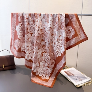 Detail view of retro rust-red square silk scarf with elegant floral prints and fine draping