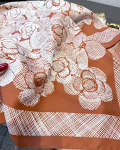 Close-up of silk-like scarf with orange floral print and premium twill texture detail