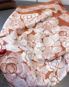 Detail of caramel silk scarf with white camellia flower prints and satin finish texture