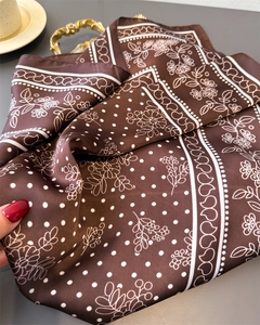 Detailed macro of coffee brown silk scarf with floral patterns and wavy heart borders