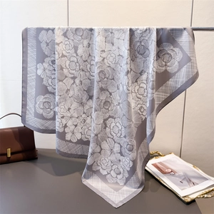 Detail of silk-like square scarf with white camellia print and soft glossy drape finish