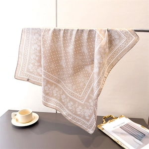 Elegant beige silk square scarf featuring floral prints hanging on a metal rack