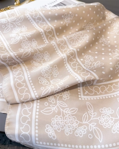 Detail shot of silk-like champagne floral scarf with elegant soft glossy texture
