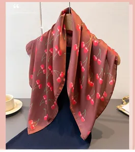 Close-up of cherry print silk scarf draped on hanger with satin sheen and smooth texture