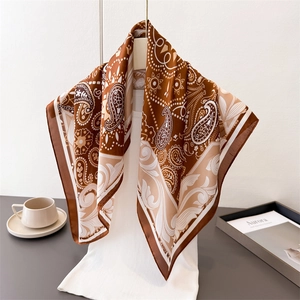 Elegant paisley silk scarf in chocolate brown and beige, displayed on a stylish hanger