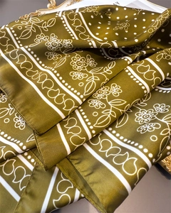 Close-up of olive green silk scarf with white floral paisley pattern and smooth texture