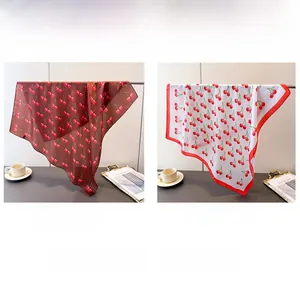 Detailed view of cherry print faux silk scarves in dark red and white patterns