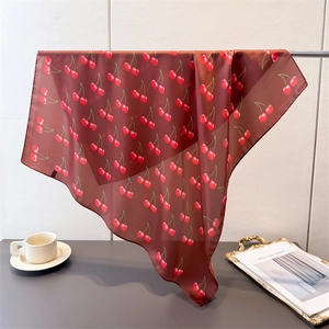 Elegant brown silk scarf with red cherry print hanging on a metal rack for a vintage style