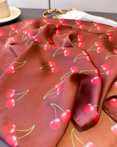 Detail of silk-like satin scarf featuring cherry prints and neat hemmed edges