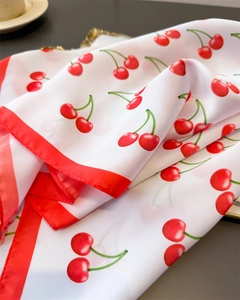 Detailed view of white silk scarf with red cherry print and premium satin finish