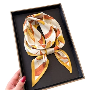 Foulard en soie aux motifs de fruits orange et jaune, plié dans son coffret
