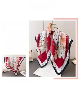 Detail of elegant silk square scarf with red floral patterns and classic black polka dots