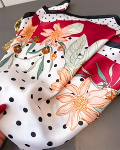 Detail view of floral and polka dot silk scarf showing smooth texture and red contrast border