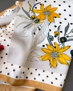 Macro shot of satin silk scarf featuring yellow floral patterns and classic polka dots