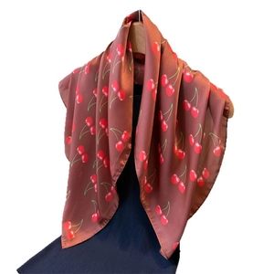 Elegant cherry print silk-like satin square scarf hanging on a wooden hanger with blue shirt