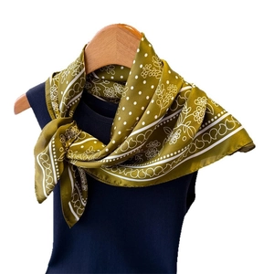 Olive green silk-like floral scarf with white polka dots on a navy knit sweater