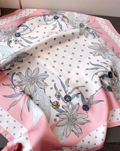 Detail of silk-like scarf showing elegant floral patterns and polka dots on premium fabric