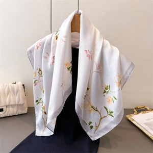 Élégant foulard en soie avec imprimé magnolia sur un cintre en bois pour femme