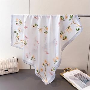 Détail d'un foulard en soie blanche avec imprimé floral de magnolia et bordure grise
