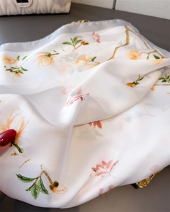 Détail d'un foulard effet soie avec imprimé magnolia et texture perlée douce