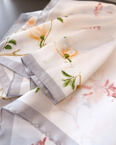 Vue détaillée d'un élégant foulard en soie blanche avec motifs de magnolia et bords roulés