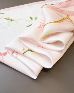 Vue détaillée d'un foulard en soie rose avec d'élégants motifs de magnolia et lustre satiné
