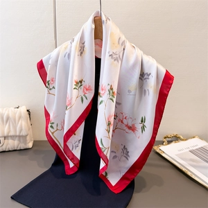 Élégant foulard en soie imprimé floral blanc avec bordure rouge sur un cintre en bois