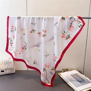 Détail d'un élégant carré de soie avec imprimé floral et bordure en satin rouge foncé