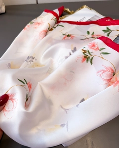 Détail d'un foulard en soie aux motifs floraux élégants et bordures rouges vives