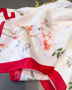 Détail d'un foulard en soie avec imprimés de magnolia et une bordure rouge élégante