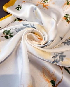 Vue macro d'un foulard en soie aux motifs floraux orange et texture satinée lisse