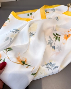 Détail de l'imprimé fleuri élégant sur foulard en soie satinée avec bords jaunes