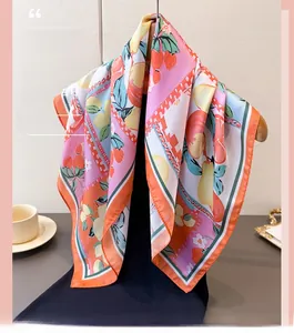 Detail of silk scarf featuring vibrant lemon and floral print on a wooden hanger