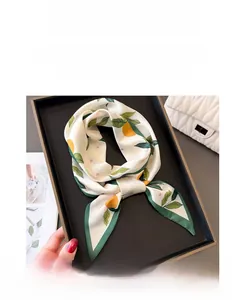 Detailed view of silk-texture orange print skinny scarf styled with a white quilted bag