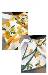 Close-up of summer lemon and citrus print silk-feel scarves with vibrant color borders