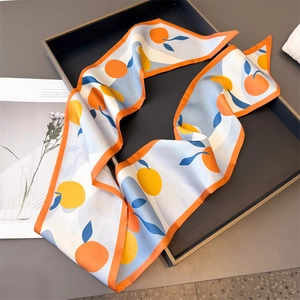 Detailed macro view of silk twilly scarf with orange print and blue leaf patterns