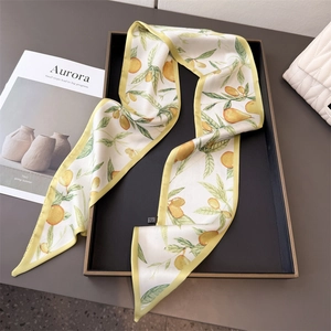 Elegant white satin twilly scarf with yellow citrus print on a minimalist black tray