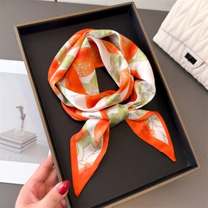 Silk scarf with vibrant orange fruit print on a tray with white quilted bag