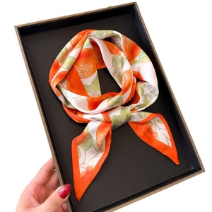Silk-like scarf with vibrant orange citrus prints and green leaves in a gift box