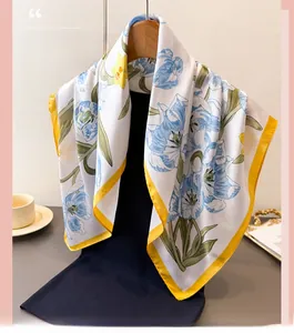 Detailed view of tulip floral pattern silk scarf with vibrant yellow hem on a hanger