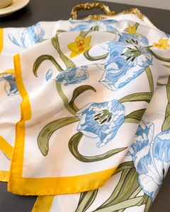 Close-up of floral silk scarf with yellow tulips and green stems on vintage tray