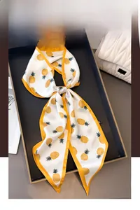 Detail of skinny silk scarf with yellow pineapple pattern and cream background tied in knot