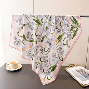 Detail of silk-like floral scarf with tulip prints and pink borders on a desk