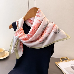 Romantic floral silk scarf in pale pink with orange blooms on a wooden hanger