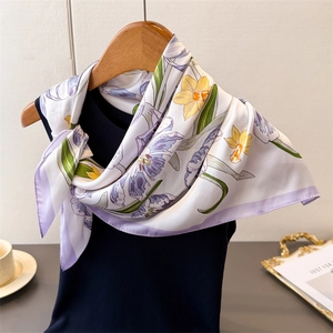 Close-up of silk-like floral scarf in purple and yellow on a wooden hanger display