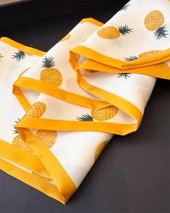 Detail of thin silk scarf featuring vibrant yellow pineapple prints and contrast borders