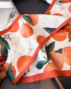 Detail of fruit print silk scarf featuring hand-painted oranges and orange stitched edges